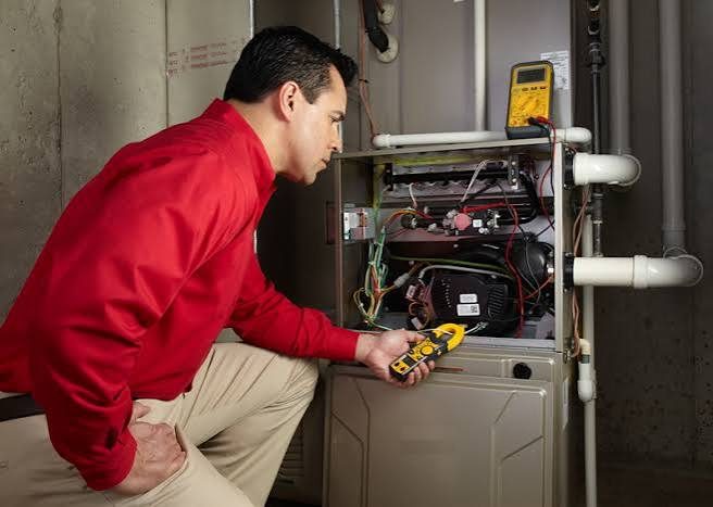Technician inspecting a residential furnace with diagnostic tools