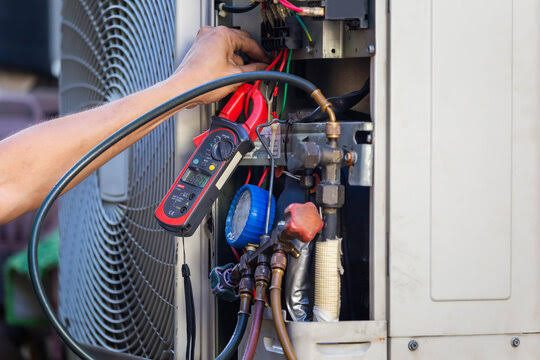 Close-up of HVAC diagnostic gauges connected to an outdoor condenser