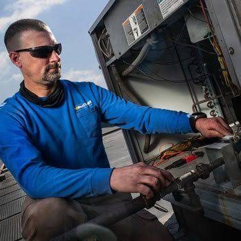 HVAC technician working on rooftop heating and cooling equipment
